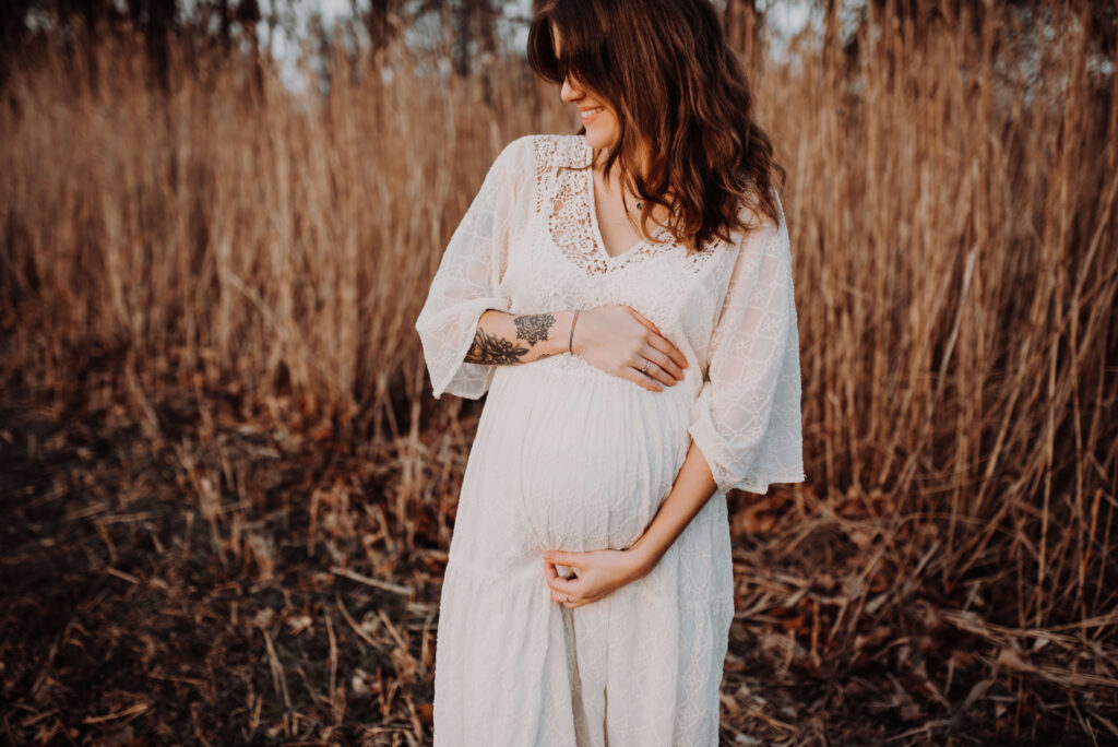 Junge Frau mit Babybauch in schönem Kleid auf einem Feld